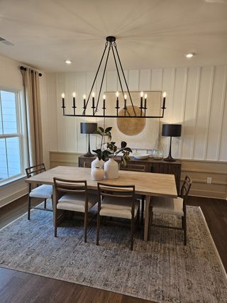 Model Home A sophisticated dining room featuring a wooden table, elegant lighting, and stylish decor accents.