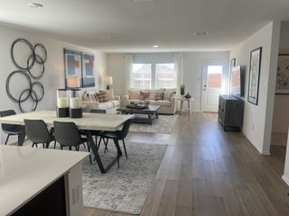 Model Home A spacious open-concept living area with stylish decor, wood-style flooring, and large windows.