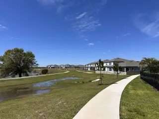 A scenic view of Silverlake by Pulte Homes (Lake Alfred, FL), showcasing beautiful waterfront homes and peaceful walking trails under Florida's blue skies.