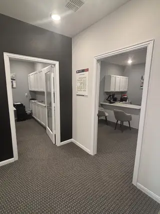 A modern office space with gray carpet, black accent wall, and sleek white cabinets.