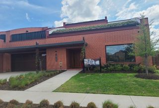 Street view A modern brick home with unique roof landscaping in Tapestry by Total Environment Homes (Frisco, TX).