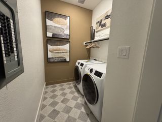 Model Home A functional laundry room with modern appliances, abstract artwork, and checkered flooring for a stylish touch.
