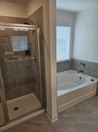 A spa-like bathroom with a glass-enclosed shower, a deep soaking tub, and modern tile finishes.

