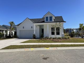 A charming white home with a gabled roof and manicured lawn in Point Hope by Pulte Homes (Charleston, SC).