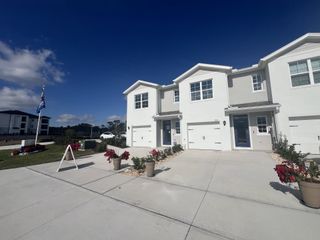 Charming white townhomes with manicured lawns in Danbury at Ridgewood Lakes by D.R. Horton (Davenport, FL).