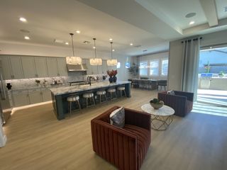 Luxurious open kitchen with marble island, chic cabinetry, and cozy seating area. Bright dining space with patio access.