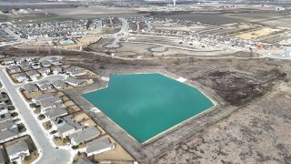Aerial view of Emory Crossing 40s by Taylor Morrison with a serene pond and developing neighborhood in Hutto, TX.