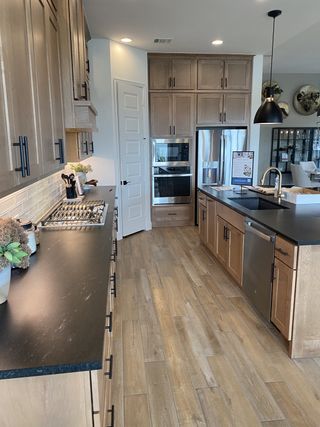 Model Home A modern kitchen with sleek black countertops, light wood cabinets, and stainless steel appliances.