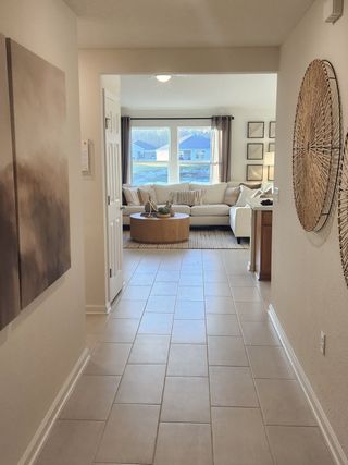 A welcoming hallway with modern art leads to a bright living room featuring a cozy sectional and natural light.