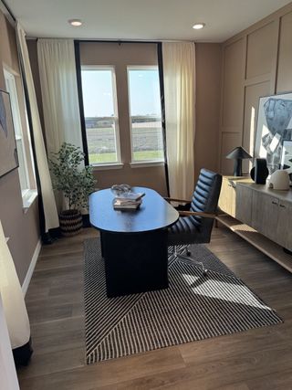 A modern home office with sleek furniture, warm lighting, and large windows for natural light.