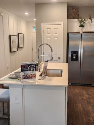 Model Home A modern kitchen featuring a sleek island with a high-arc faucet, stainless steel appliances, and elegant decor.