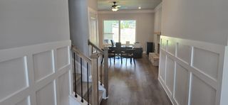 A welcoming hallway with wood flooring, leading to a bright room with a brick fireplace and large window.