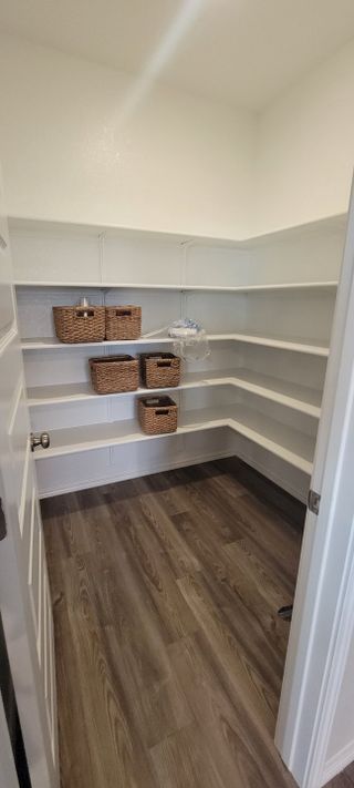 Model Home A spacious walk-in pantry with sleek white shelving and stylish wood flooring.