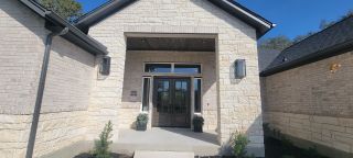 Elegant stone entryway with modern lighting in Pradera Ridge by Joseph Creek Homes (Floresville, TX).
