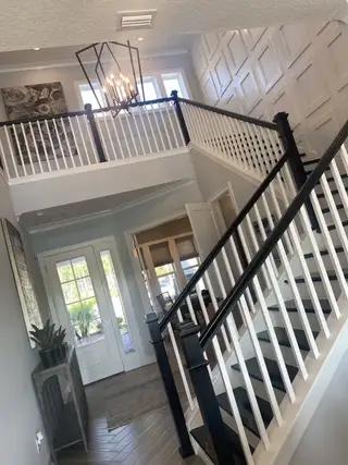 A welcoming entryway featuring elegant stairs, large windows, and modern lighting, creating a bright and airy atmosphere.