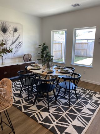 A bedroom with a bold black accent wall, decorative wooden flowers, a metal frame bed with patterned pillows, and white wainscoting.