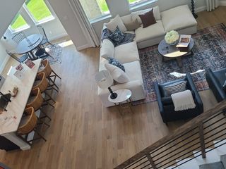 A chic living area with a cozy white sectional, elegant round table, and bar seating on warm wood flooring.