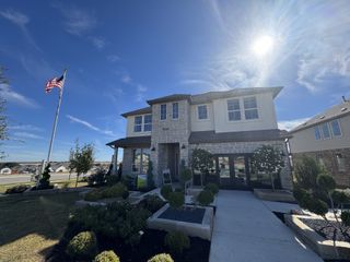 Street view A beautiful stone and brick home with manicured landscaping in Capitol Collection at Lariat by Tri Pointe Homes (Liberty Hill, TX).