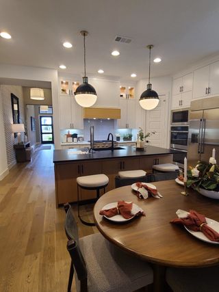 A modern kitchen with pendant lights, elegant cabinetry, an island, and a cozy dining area featuring a round table.