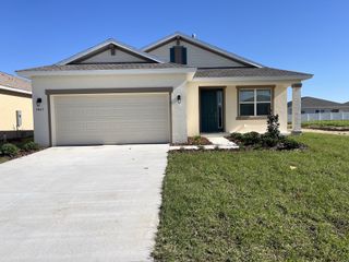 A charming beige home with a two-car garage and neat lawn in Calesa Township by Colen Built Development, LLC (Ocala, FL).