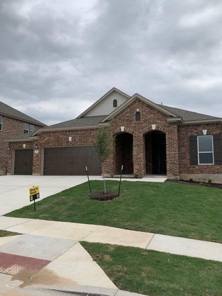 A move-in ready brick home in Salerno by KB Home (Round Rock, TX) features a well-manicured lawn and a double-arched entryway, signifying immediate availability.