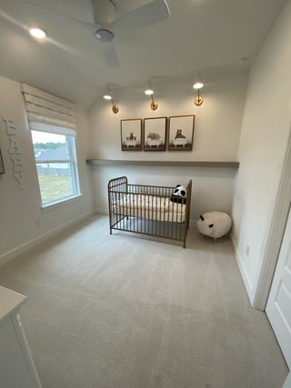 A cozy nursery with soft carpeting, a modern crib, and charming wall art under warm lighting.