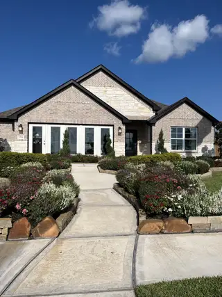 Street view A charming brick home with lush landscaping in Lago Mar by M/I Homes (Santa Fe, TX).