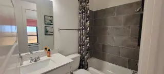 Stylish guest bath featuring a tub-shower combo, gray tiled walls, and modern fixtures for a sleek, functional space.