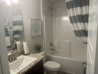 A modern bathroom with granite countertop, striped shower curtain, sleek fixtures, and stylish decor.