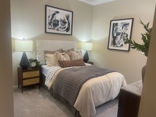 A cozy bedroom features plush bedding, abstract art, and warm lighting, creating a serene and inviting atmosphere.