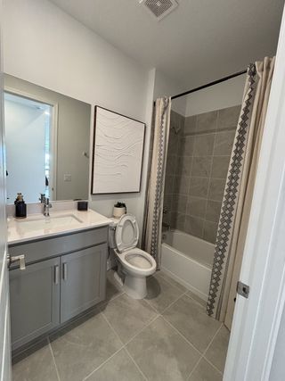 A modern bathroom with a sleek vanity, tiled floor, and elegant shower curtain accents.