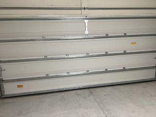 A spacious garage with a clean concrete floor and a sleek sectional white door.