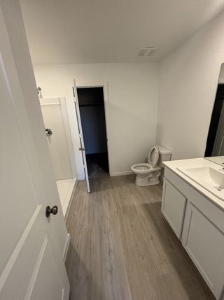 A modern bathroom with sleek flooring, white cabinetry, a shower, and a practical layout for everyday convenience.