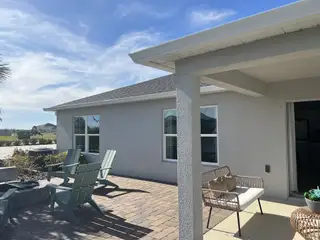 A beautiful patio with cozy seating and blue skies in Gardens at Waterstone II by KB Home, Palm Bay, FL.