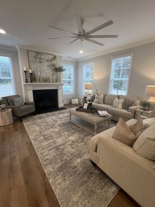 A cozy living room with a plush area rug, elegant sofas, a chic coffee table, and a modern ceiling fan.