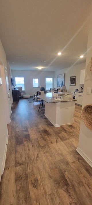 A spacious, open-concept living area with hardwood-style flooring leads to a kitchen with a large island and a bright living space.