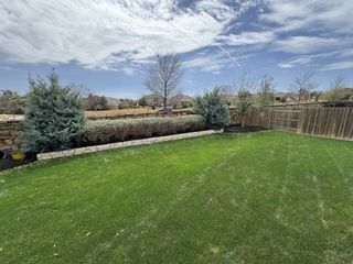 Model Home A lush backyard with a manicured lawn, stone-lined garden beds, and privacy fencing for peaceful outdoor living.