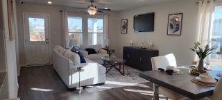 Model Home A cozy living room with plush sofas, elegant decor, and a stylish dining area, exuding warmth and modern charm.