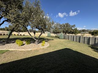 Model Home A serene backyard with lush greenery and a stone wall in Wolf Ranch 56' by Perry Homes (Georgetown, TX).