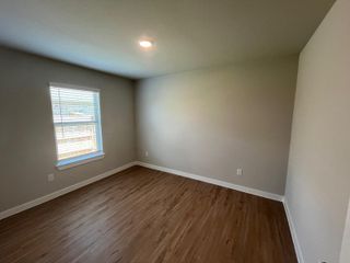A bright, cozy room with wood flooring, soft beige walls, and a window with blinds. Perfect for various design options.