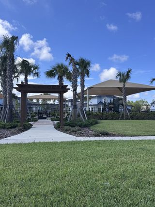 Community Amenities A picturesque community entrance with palm trees and a pergola at Crosswinds 40' Paired Villas by David Weekley Homes (Ponte Vedra, FL).