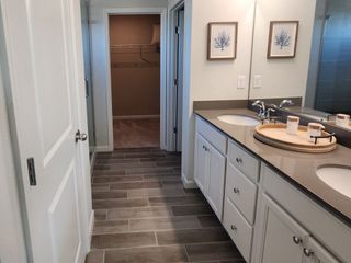 A sleek bathroom featuring dual sinks on a quartz countertop, elegant cabinetry, and stylish tile flooring.
