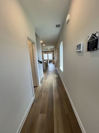 Model Home A long, inviting hallway with sleek wood flooring leading to a bright living space.
