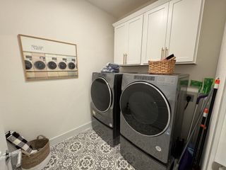 A sleek laundry room with modern appliances, patterned tile flooring, and ample cabinet storage.