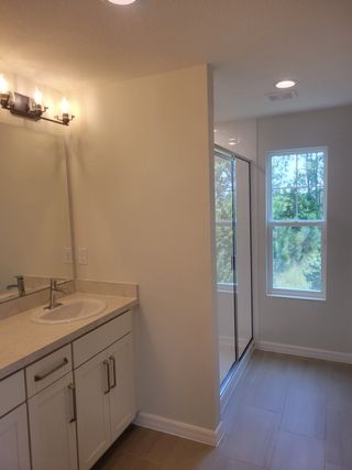 A bright bathroom with sleek cabinetry, a spacious vanity, and a glass-enclosed shower accented by natural light.