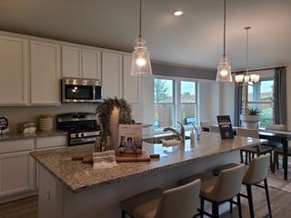 A modern kitchen with granite countertops, stainless steel appliances, and elegant pendant lighting illuminating a spacious island.