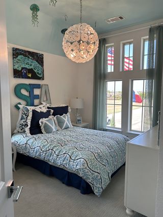 A coastal-themed bedroom with sea-inspired decor, plush bedding, and a unique globe chandelier.