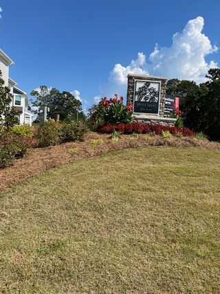 Street view A charming entrance with vibrant flowers and a welcoming sign at Sweetbay Farm by Fischer Homes in Lawrenceville, GA.