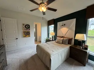 Model Home A cozy bedroom with a feature wall, large windows, and warm lighting.