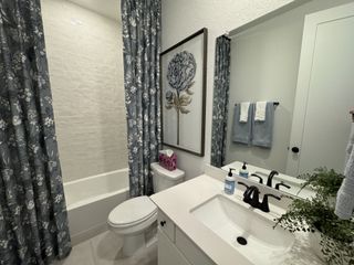 A modern bathroom featuring a white bathtub, floral-patterned shower curtains, and sleek black fixtures.